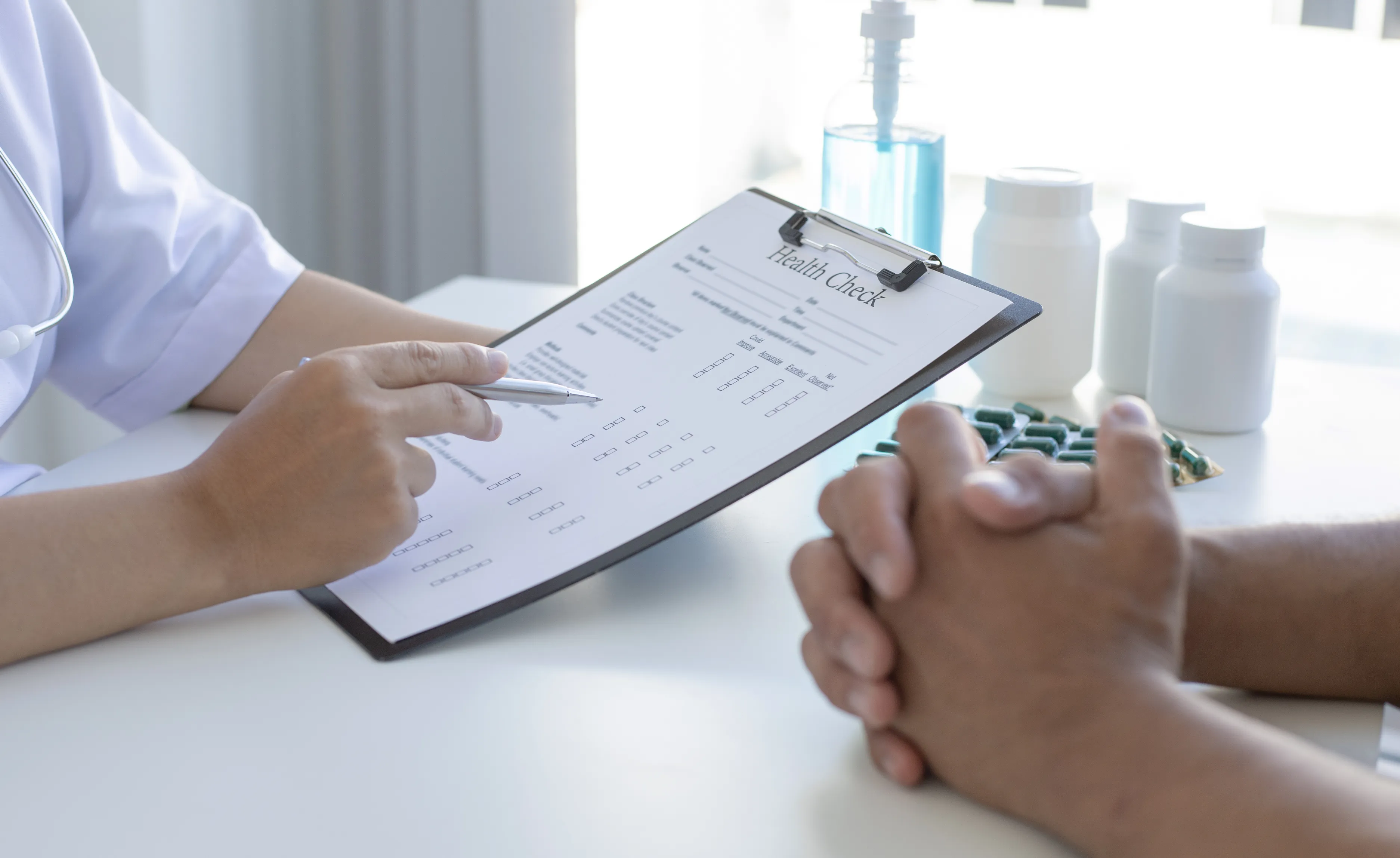 A healthcare professional in a white coat reviewing a health check form with a seated patient.